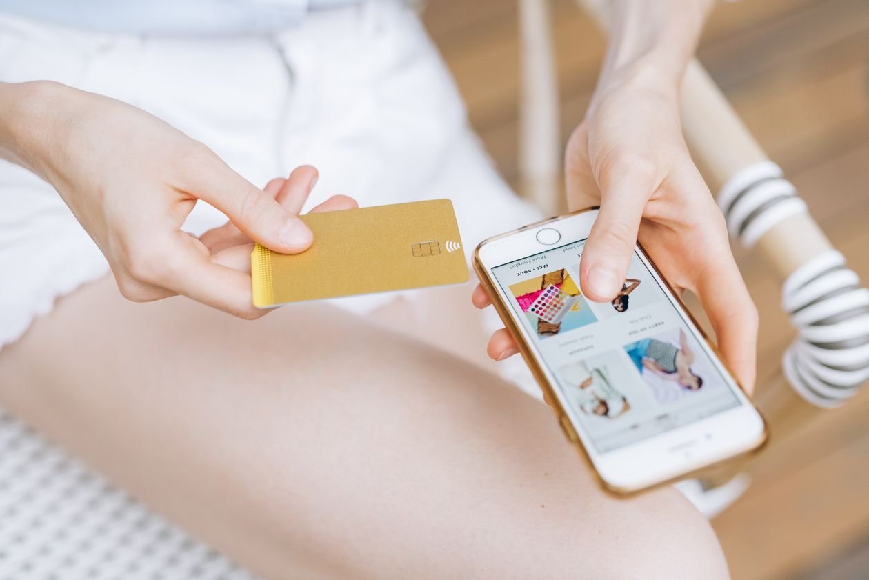 Woman holding a smartphone and bank card while completing an online loan application