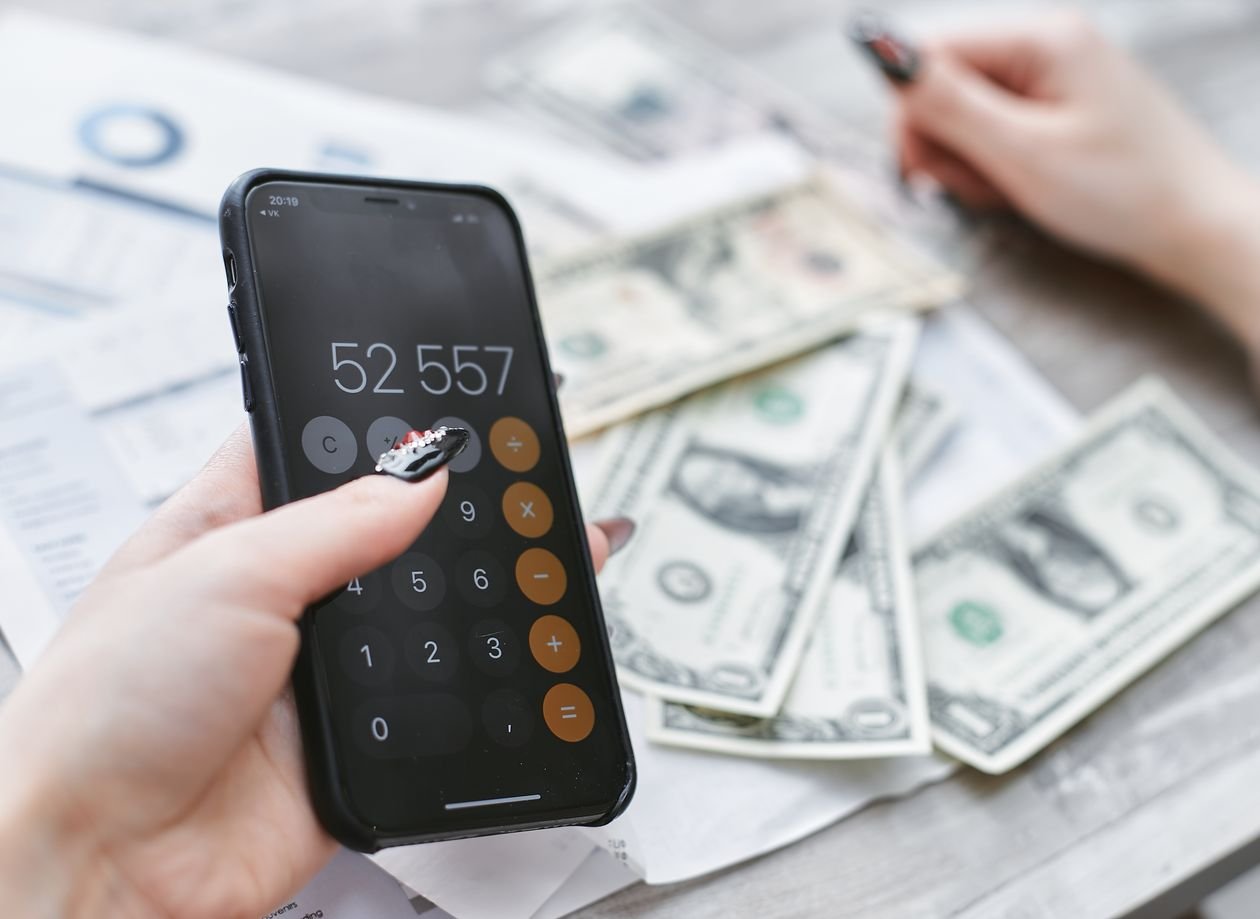 Person holding a phone while counting cash and checking a mobile banking app for a short-term loan