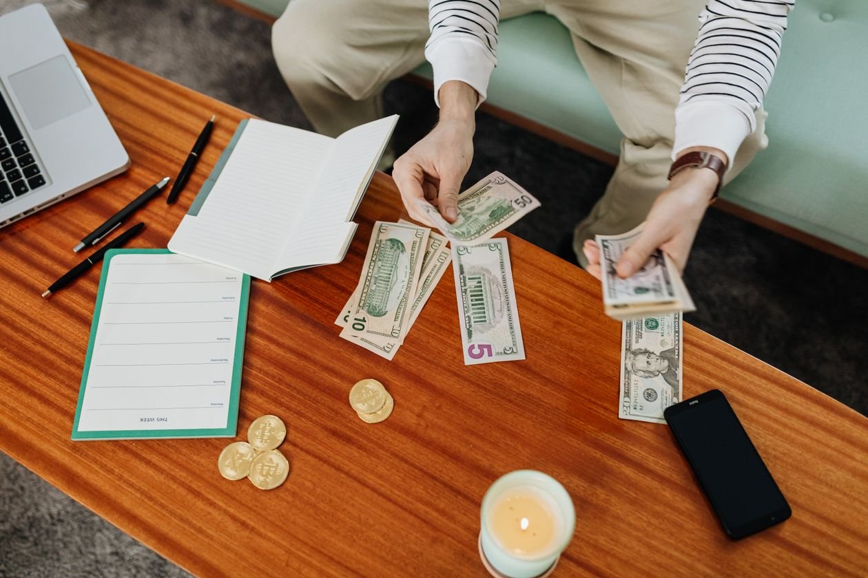 Person budgeting household money with notes and cash after SafetyNet Credit closed