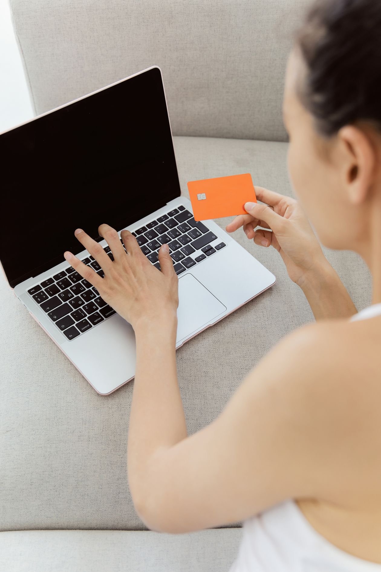 Woman holding a bank card while using a laptop to access her online savings account
