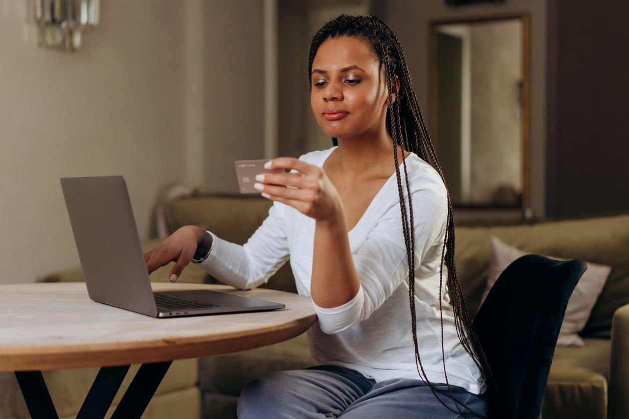 Woman using a laptop and bank card to complete an online loan application