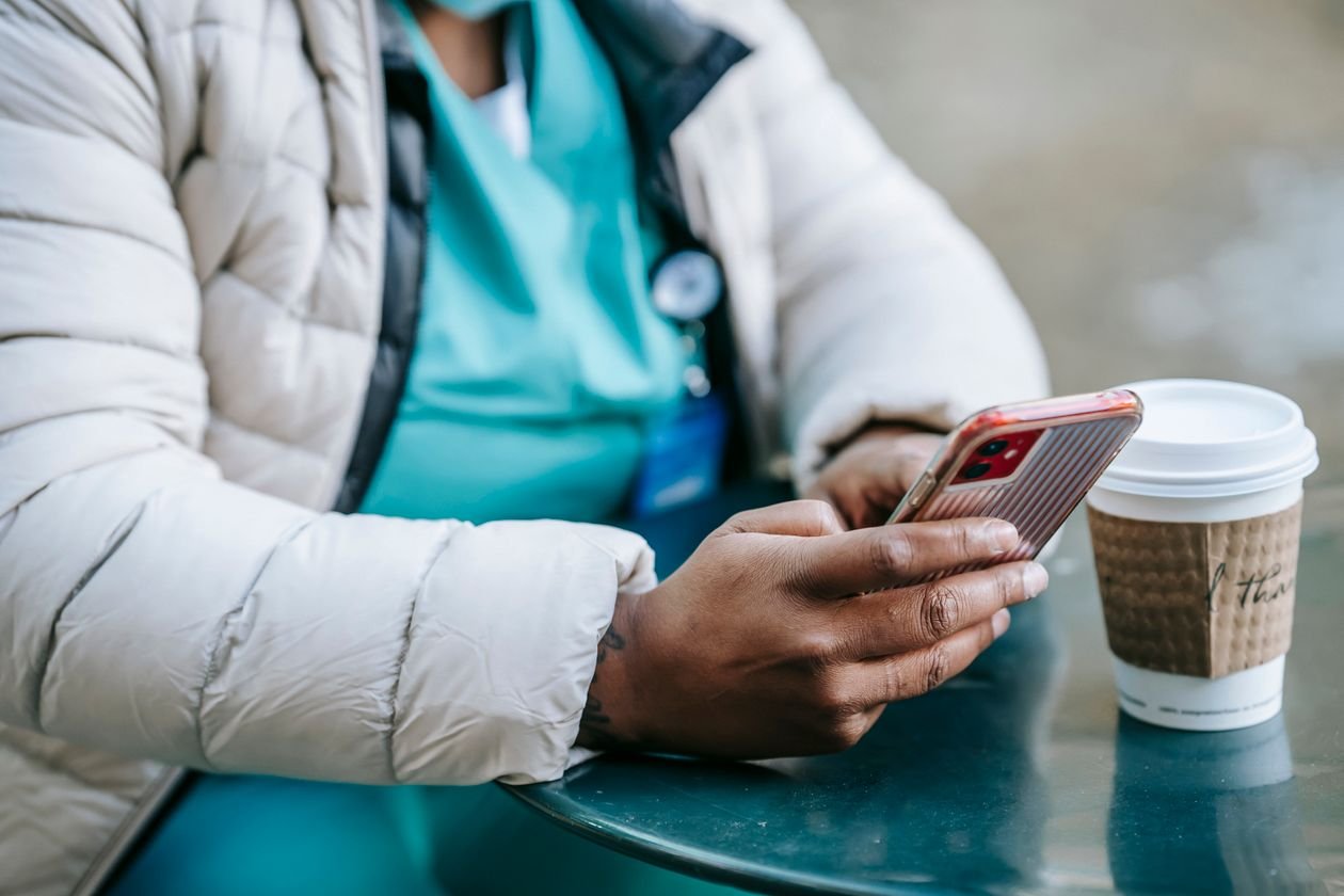 Healthcare worker checking a smartphone on a break while considering a personal loan