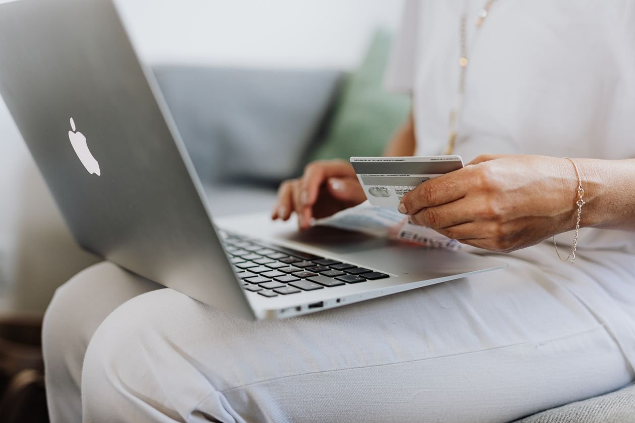 Hands holding a credit card beside a laptop to make an online payment and build credit