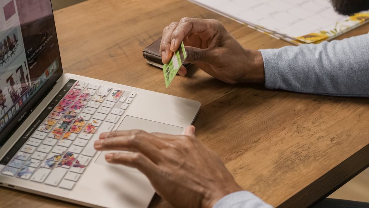 Person typing on a laptop while holding a credit card to check card eligibility online